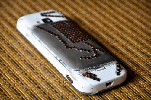 晶晶的手机后盖已经被摔裂，用透明胶带粘了起来。手机背面贴了一排排钻石形状的装饰物，有些已经剥落